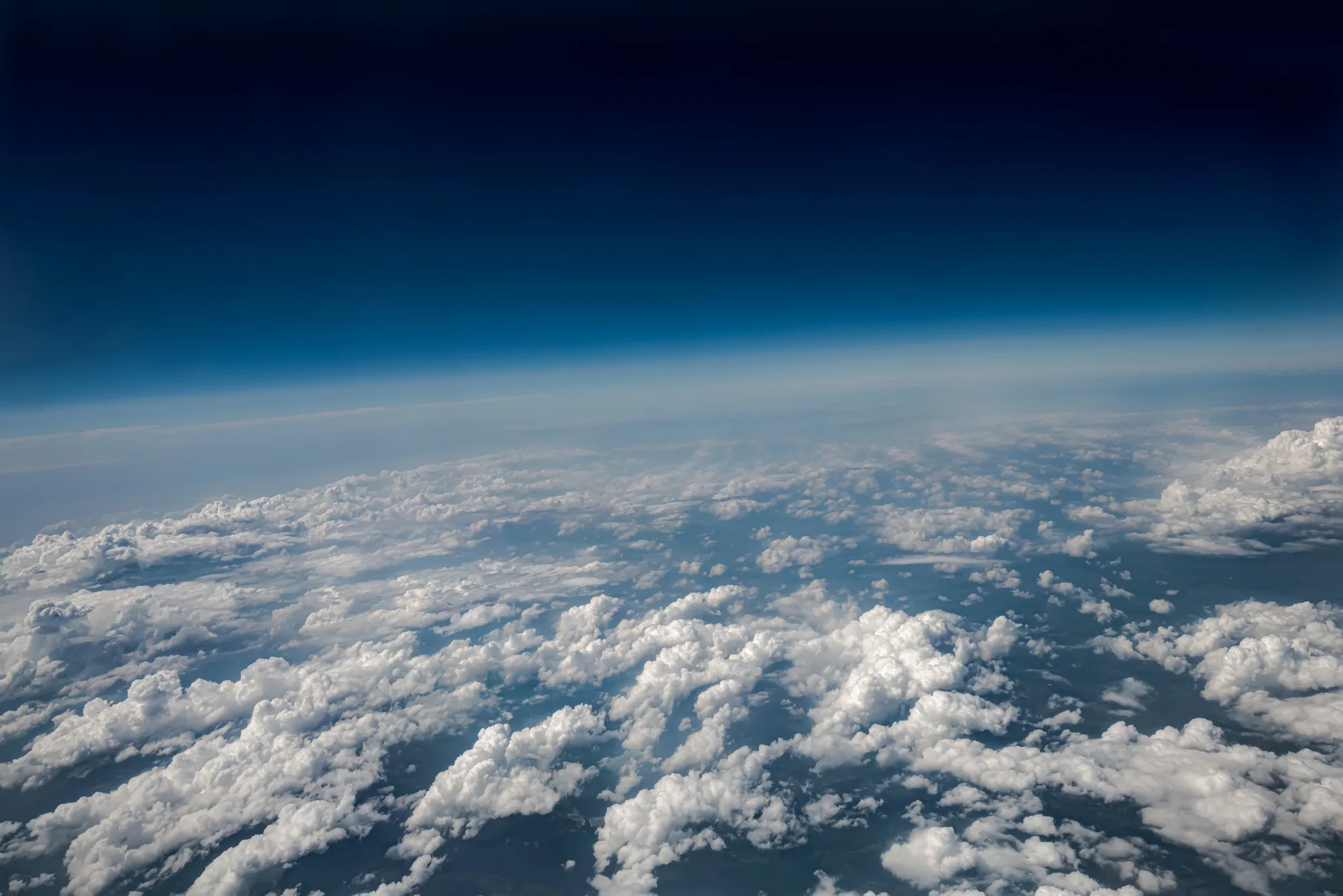 Vista aérea de un cielo despejado con nubes blancas y el horizonte curvado.